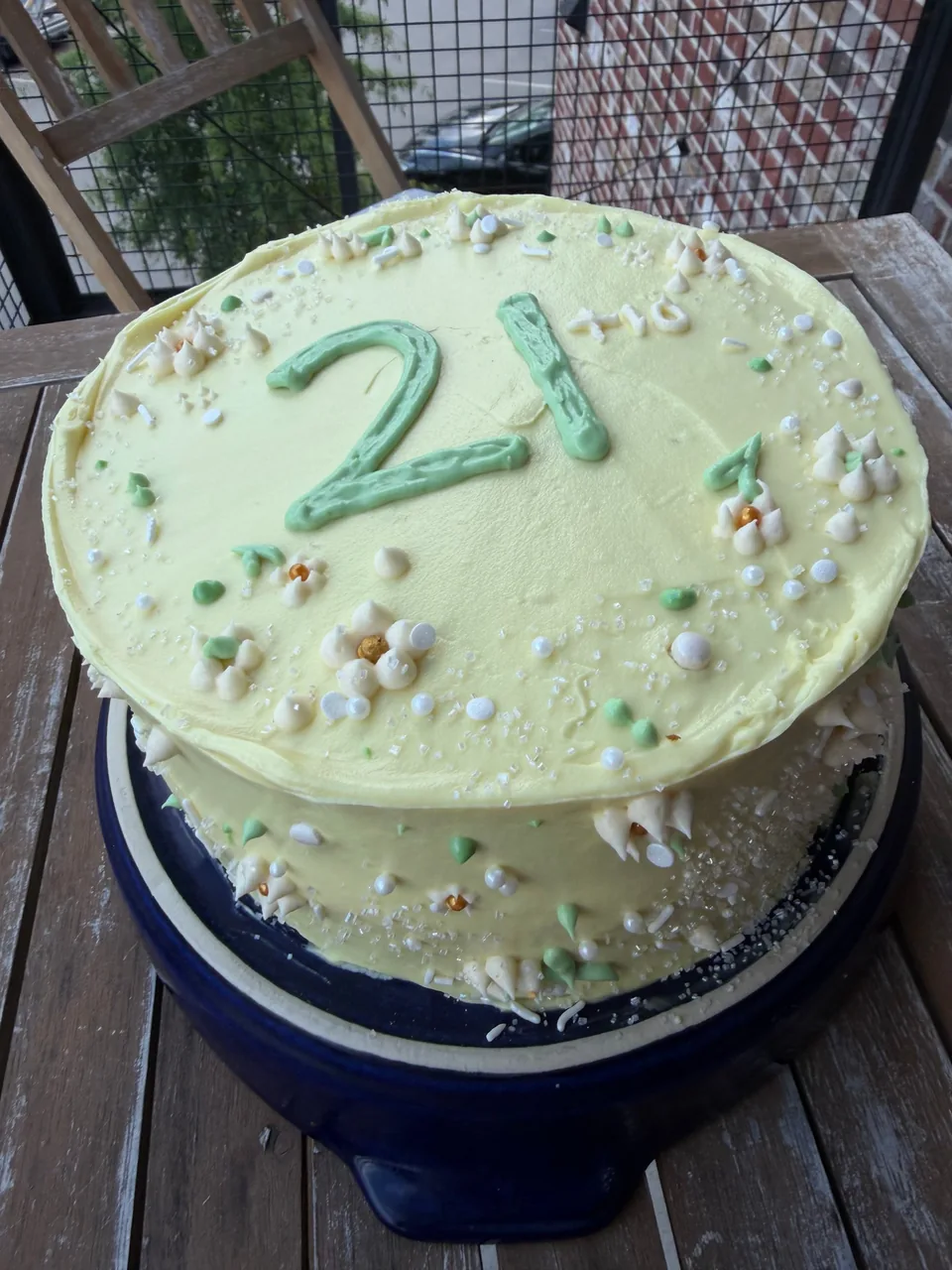 Yellow buttercream birthday cake with a green piped 21, buttercream flowers and sprinkles