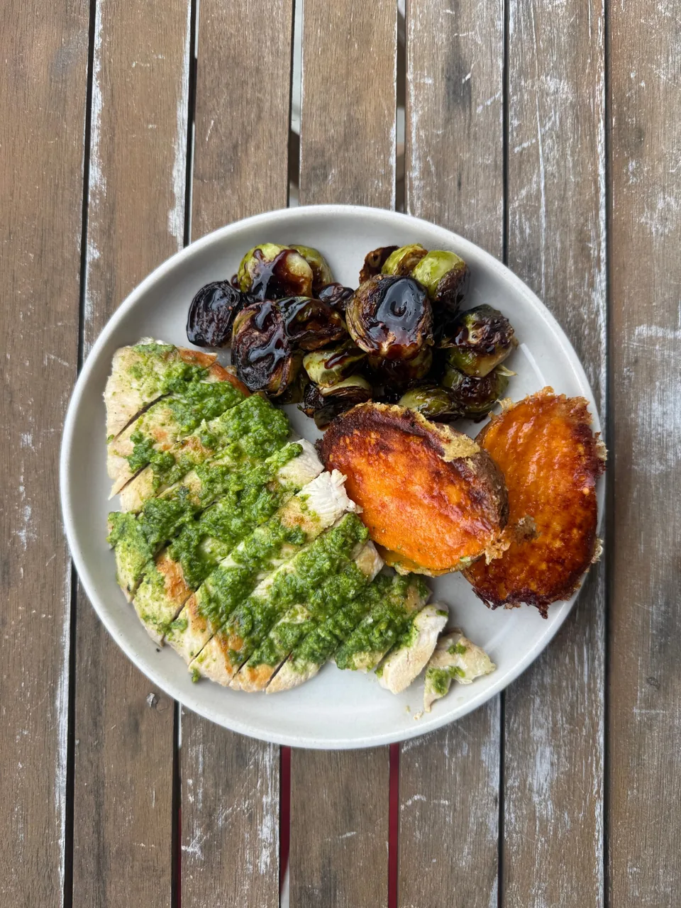 Sliced chicken breast with green herb sauce, balsamic-glazed brussels sprouts and crispy sweet potato halves
