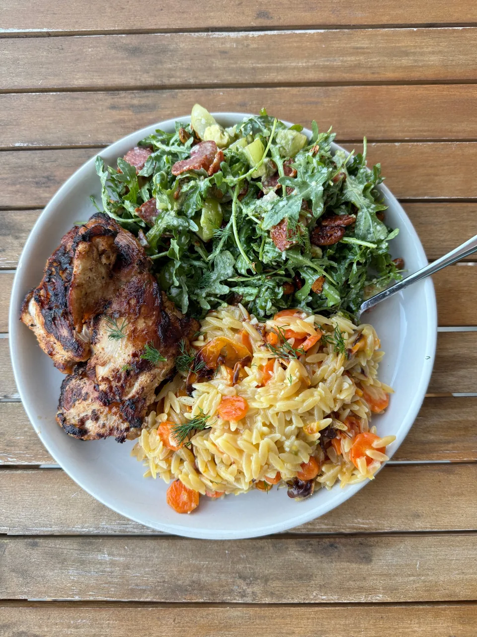 Grilled chicken thigh with an arugula salad of salami and pecans, and orzo with carrots and dill