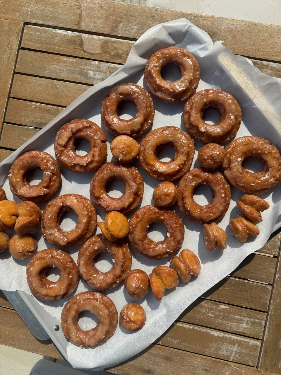 Tray of glazed old-fashioned donuts and donut holes on parchment