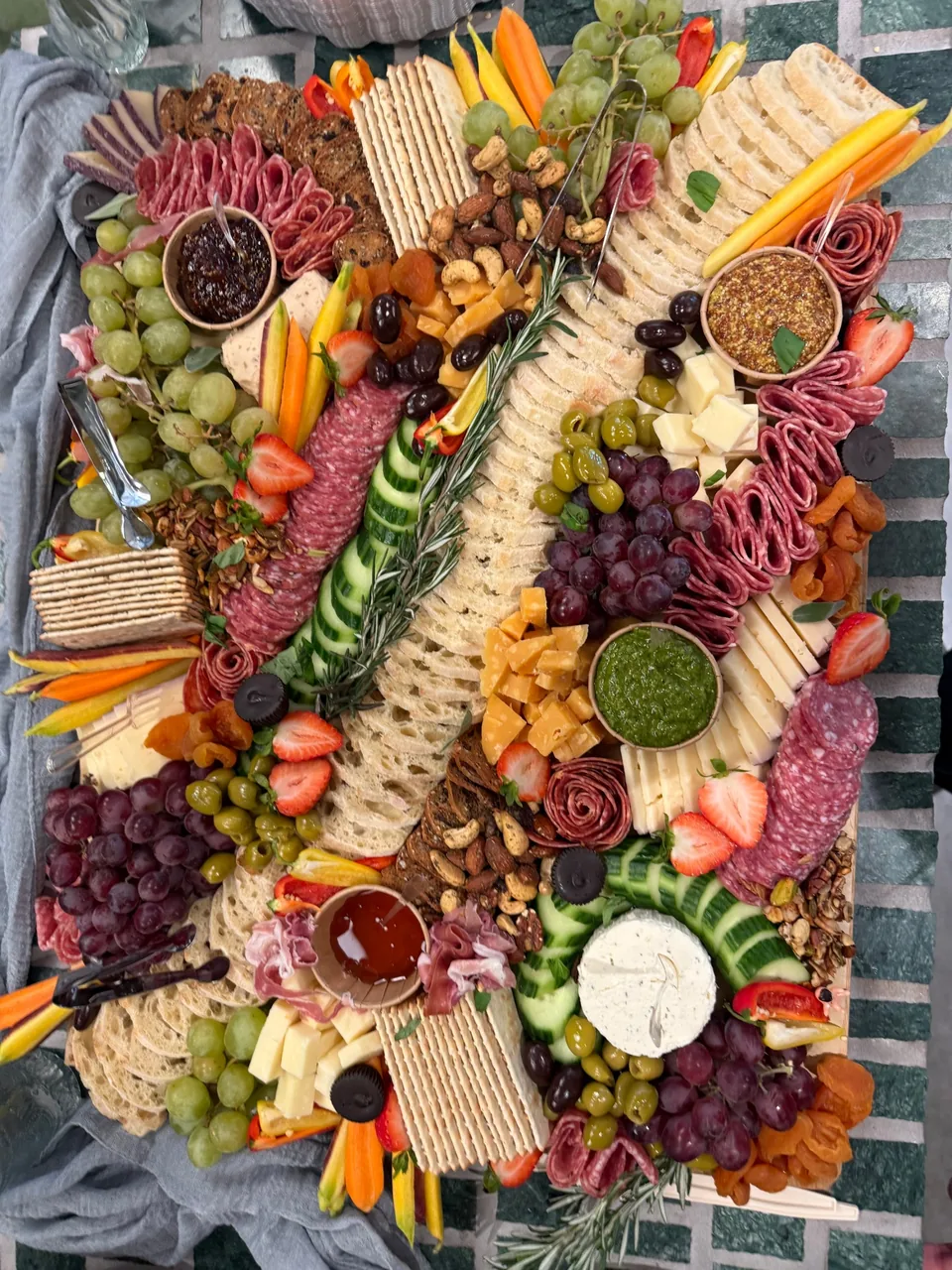 Grazing board with salami roses, cheeses, olives, grapes, apricots, honey, pesto and mustard