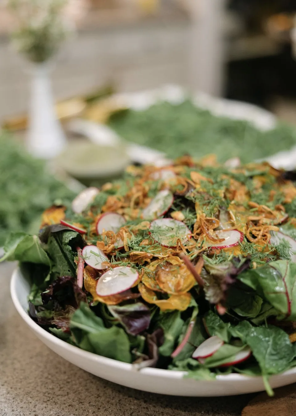 Close-up of mixed greens with shaved radish, dill and crispy shallots
